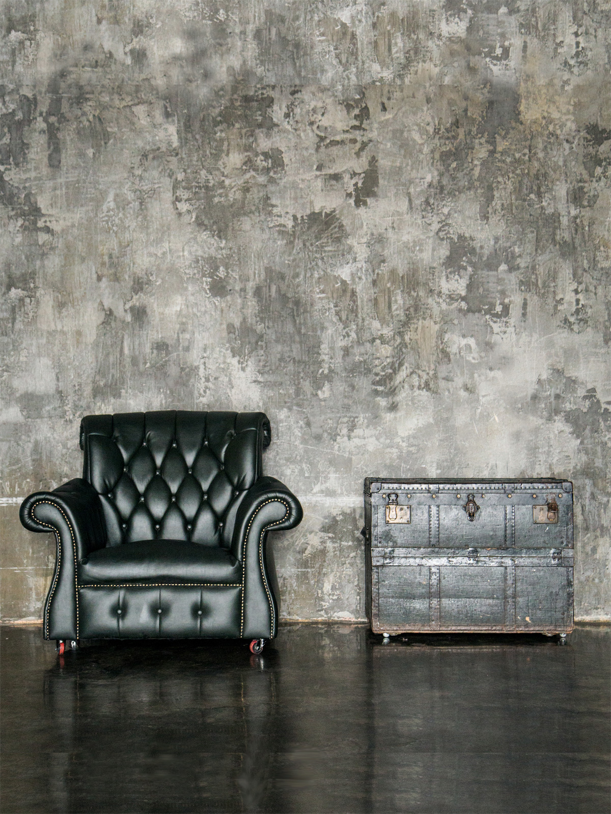 black leather chair and antique trunk with grunge textured wall